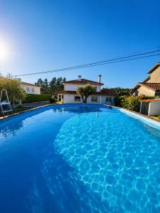 a large blue swimming pool in front of a house at Casa Corujeira in Santa