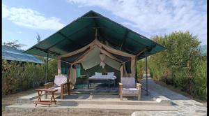 a canopy tent with a bed and two chairs at Oloibormut in Sekenani
