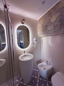 a bathroom with a sink and a toilet and a mirror at Cinquestelle Albergo del centro storico in Palinuro