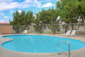 a swimming pool with two chairs and a fence at Howard Johnson by Wyndham Modesto Ceres in Ceres