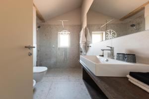 a white bathroom with a sink and a toilet at Essa Rooms NEW in Caldaro