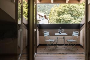 a patio with a table and chairs on a balcony at Essa Rooms NEW in Caldaro