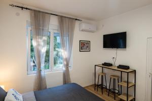 a bedroom with a bed and a tv and a window at Naissus Apartments in Niš