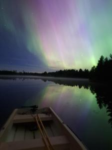 a boat on a lake under the northern lights at Historic lakeside villa - sauna, ski, boat, 20 guests in Sunnansjö
