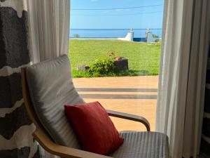 a chair with a red pillow sitting in front of a window at Blue Whale Appartment in Horta