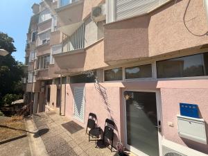 a pink building with chairs sitting outside of it at Hugo s home, apartman blizu bazena i bolnice in Krapinske Toplice