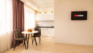 a kitchen with a table and chairs and a tv on a wall at Студия Назарбаева 57 in Kokshetau