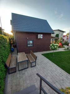 a patio with two benches and a building at Amelia Domek letniskowy in Mechelinki