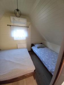 two beds in a small room with a window at Amelia Domek letniskowy in Mechelinki