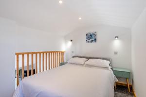 a bedroom with a white bed and a wooden crib at Kent Coast Stays - Cottages in Birchington