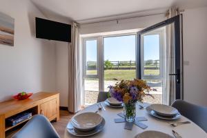 a dining room with a table with a vase of flowers at Kent Coast Stays - Cottages in Birchington