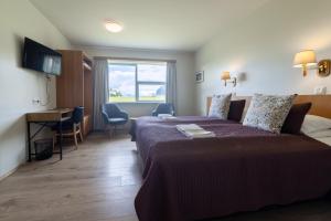 a hotel room with a bed and a desk and a window at Hali Country Hotel in Gerdi