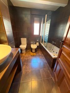 a bathroom with two toilets and a sink and a tub at posada trastamara in Piedralaves +15 photos