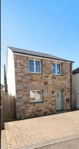 a stone house with a brick driveway in front of it at Sammy's place in Hayle