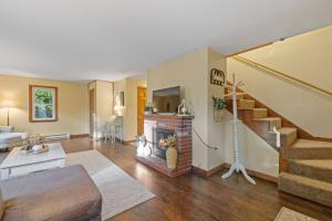 a living room with a fireplace and a staircase at Dog-Friendly Retreat, Fire Pit, Lakes Region in Gilmanton