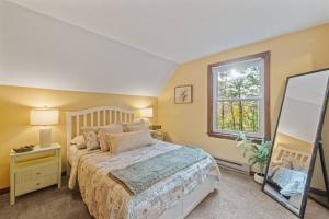 a bedroom with a bed and a window and a mirror at Dog-Friendly Retreat, Fire Pit, Lakes Region in Gilmanton