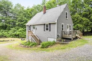 a small white house with a porch and a deck at Dog-Friendly Retreat, Fire Pit, Lakes Region in Gilmanton