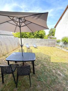 a table with an umbrella in a yard at Le Ptit Roc, cocon cosy in Chailles