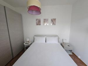 a bedroom with a white bed and a pink lamp at La sosta di Strada in Strada