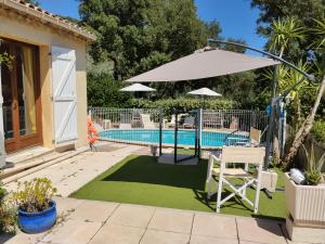 a patio with an umbrella and a swimming pool at Maison du vieux chêne in Grimaud
