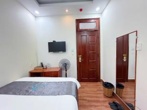 a bedroom with a bed and a tv on the wall at CaRa Hotel Đà Lạt in Da Lat