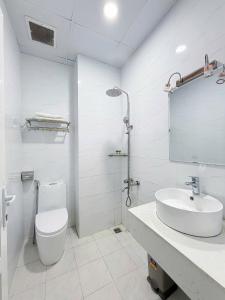 a white bathroom with a toilet and a sink at CaRa Hotel Đà Lạt in Da Lat