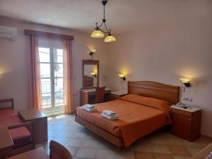 a bedroom with a bed with orange sheets and a mirror at Welcome Naxos in Agios Prokopios