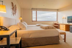 a bedroom with a bed with a desk and a window at Hotel Patagonico in Puerto Varas