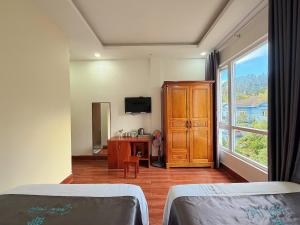 a bedroom with two beds and a dresser and a window at CaRa Hotel Đà Lạt in Da Lat