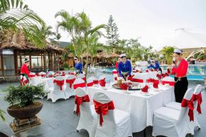 a group of people standing around tables with red bows at Hoa Binh Resort in Hòa Bình +123 photos