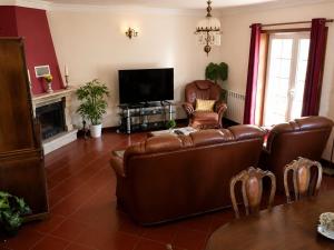 a living room with leather furniture and a flat screen tv at Casa Corujeira in Santa