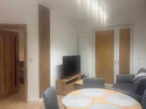 a living room with a table and a tv at Noir2 Gniezno in Gniezno