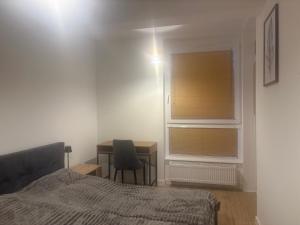 a bedroom with a bed and a desk and a window at Noir2 Gniezno in Gniezno
