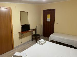 a room with two beds and a desk with a television at Hotel Tania in Casa Giosafat