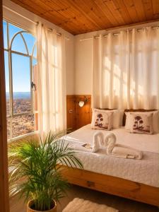 a bedroom with a large bed with a large window at Tobiana Desert Lodging Negev in ‘Ezuz