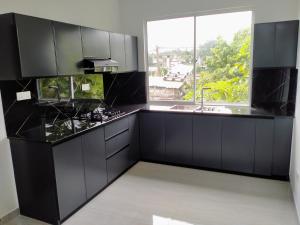 a kitchen with black cabinets and a large window at MSM Diamond Villa in Wattala