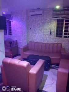 a living room with a pink couch and luggage at AAJBLissful in Idowu