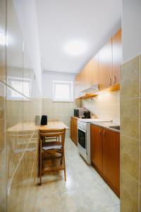 a small kitchen with a wooden table and a stove at B-G Apartments in Gheorgheni +12 photos