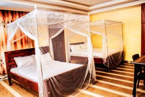 two beds in a room with mosquito nets at Armaflex hotel SMC LTD in Lira