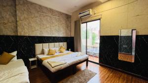 a bedroom with two beds and a large window at Elite Boutique Stays in Ujjain
