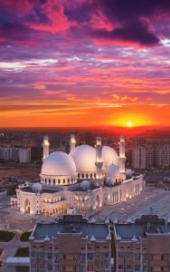a large mosque with a sunset in the background at Diamond Hotel Shymkent in Shymkent