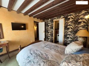 a bedroom with a bed and a tv on the wall at Maison L'étalonblanc in Tupin-et-Semons