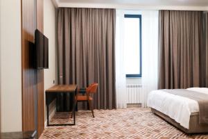 a hotel room with a bed and a desk and a bed and a bed at Diamond Hotel Shymkent in Shymkent +157 photos