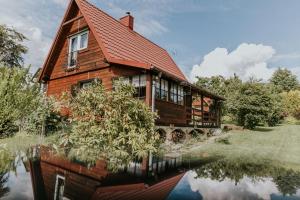 a large wooden house with a reflection in the water at Dom wakacyjny Podlas in Żywiec