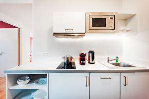 a white kitchen with a sink and a microwave at Brera Nürnberg in Nuremberg