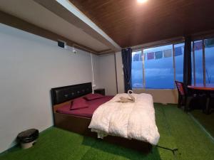 a bedroom with a bed and a table and a window at North Queen Homestay in Darjeeling