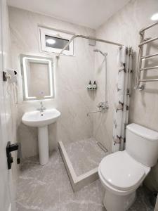 a white bathroom with a toilet and a sink at Cozy Apartment on the First Floor in Yunusobod