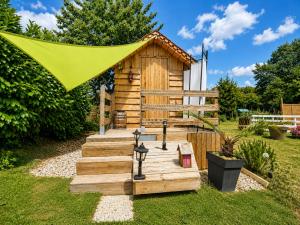 a small wooden cabin with a green tent over it at La Tiny de Lili in Draveil
