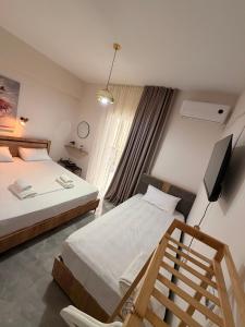 a bedroom with two beds and a flat screen tv at Rafael & Sofia Luxury Suites in Ammoudia