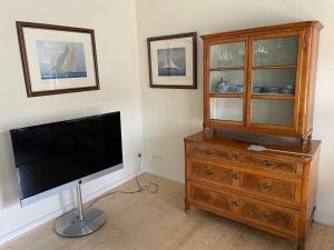 a living room with a television and a wooden dresser at Prinzenvilla in Berge